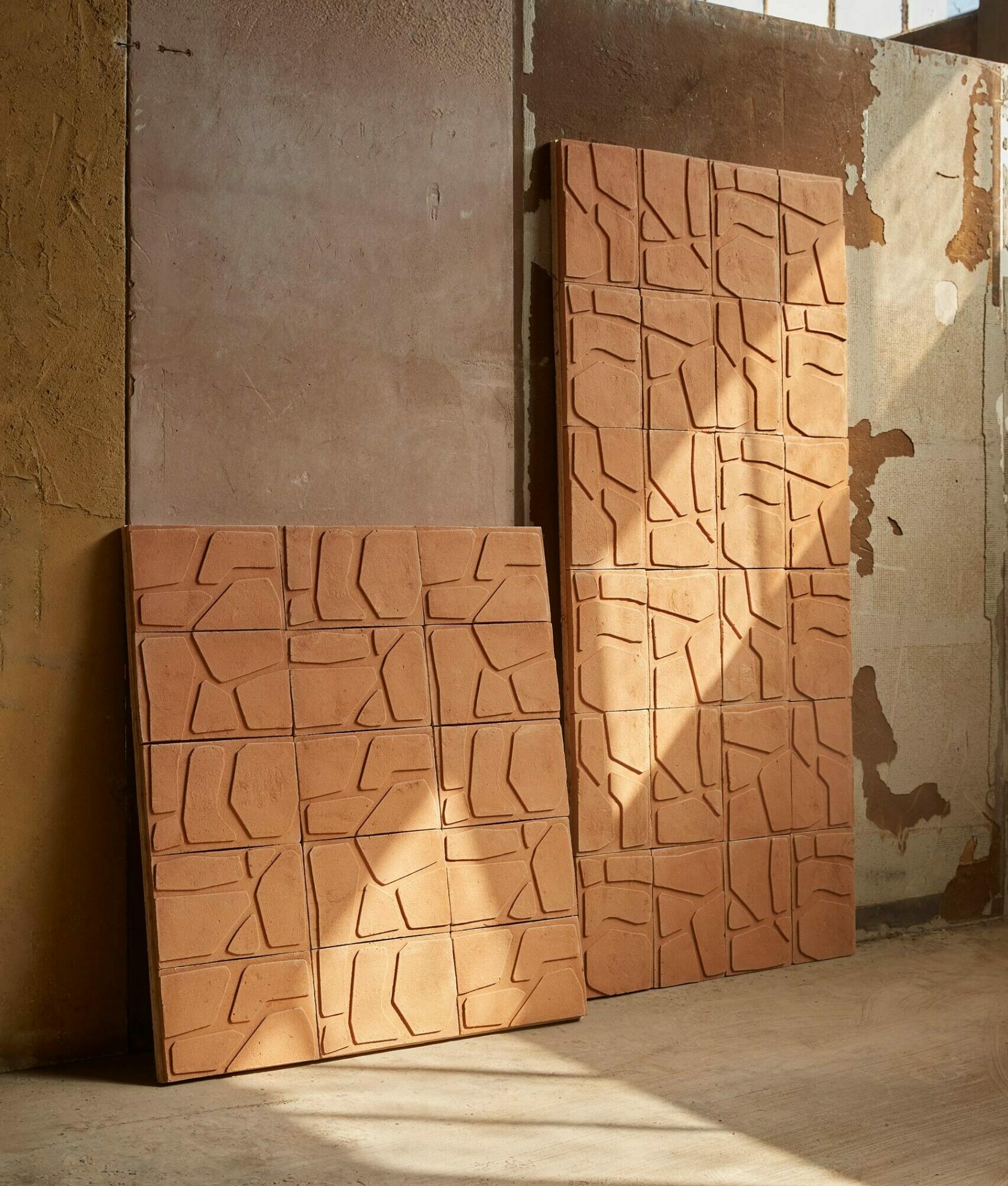 Pannelli di terracotta con motivo geometrico, appoggiati a una parete