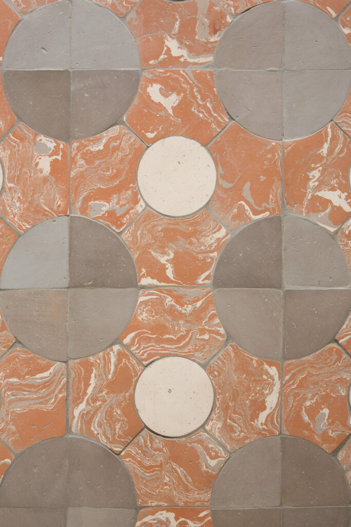 Rivestimento murale con piastrelle marroni e bianche con motivo circolare.