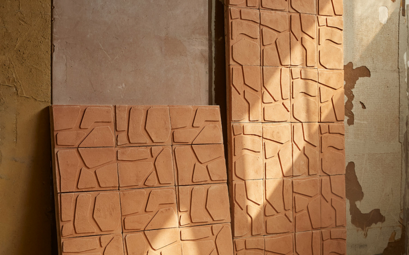 Pannelli in terracotta con motivo geometrico appoggiati a una parete in un ambiente industriale