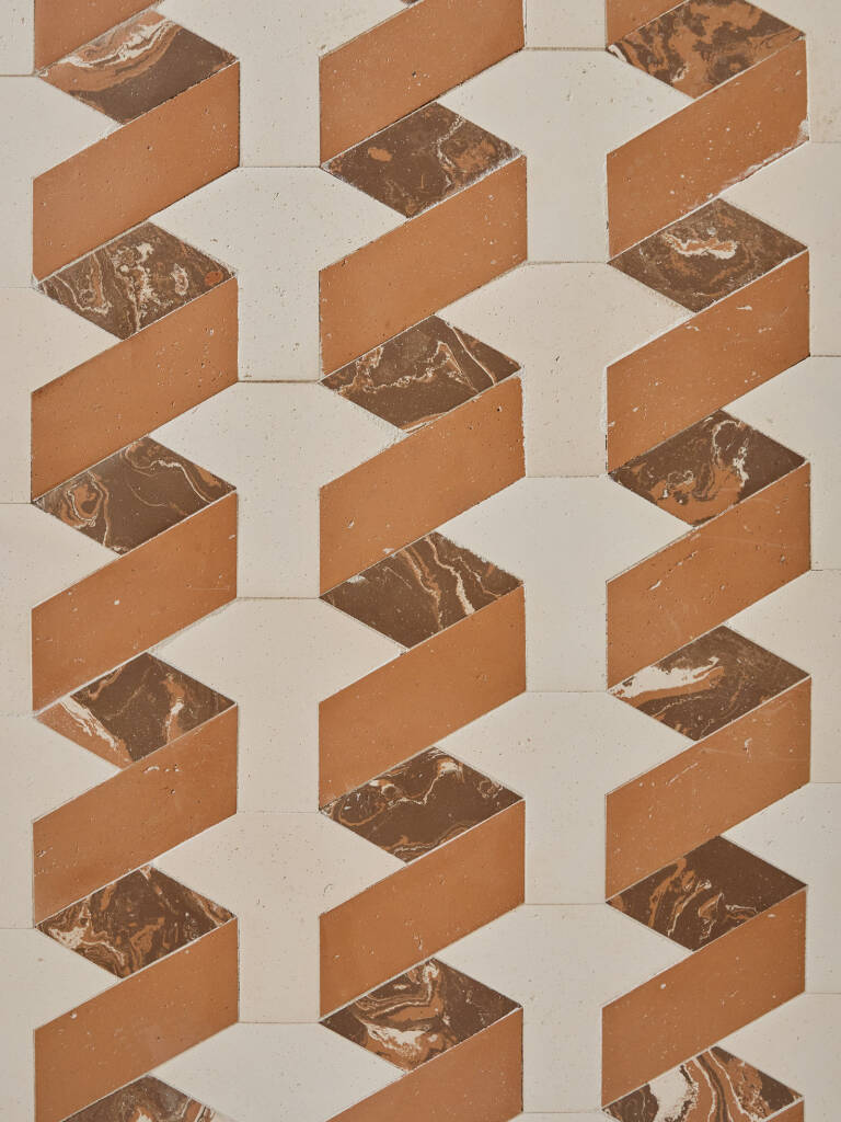 Dettaglio di pavimento geometrico in terracotta e marmo con motivi tridimensionali